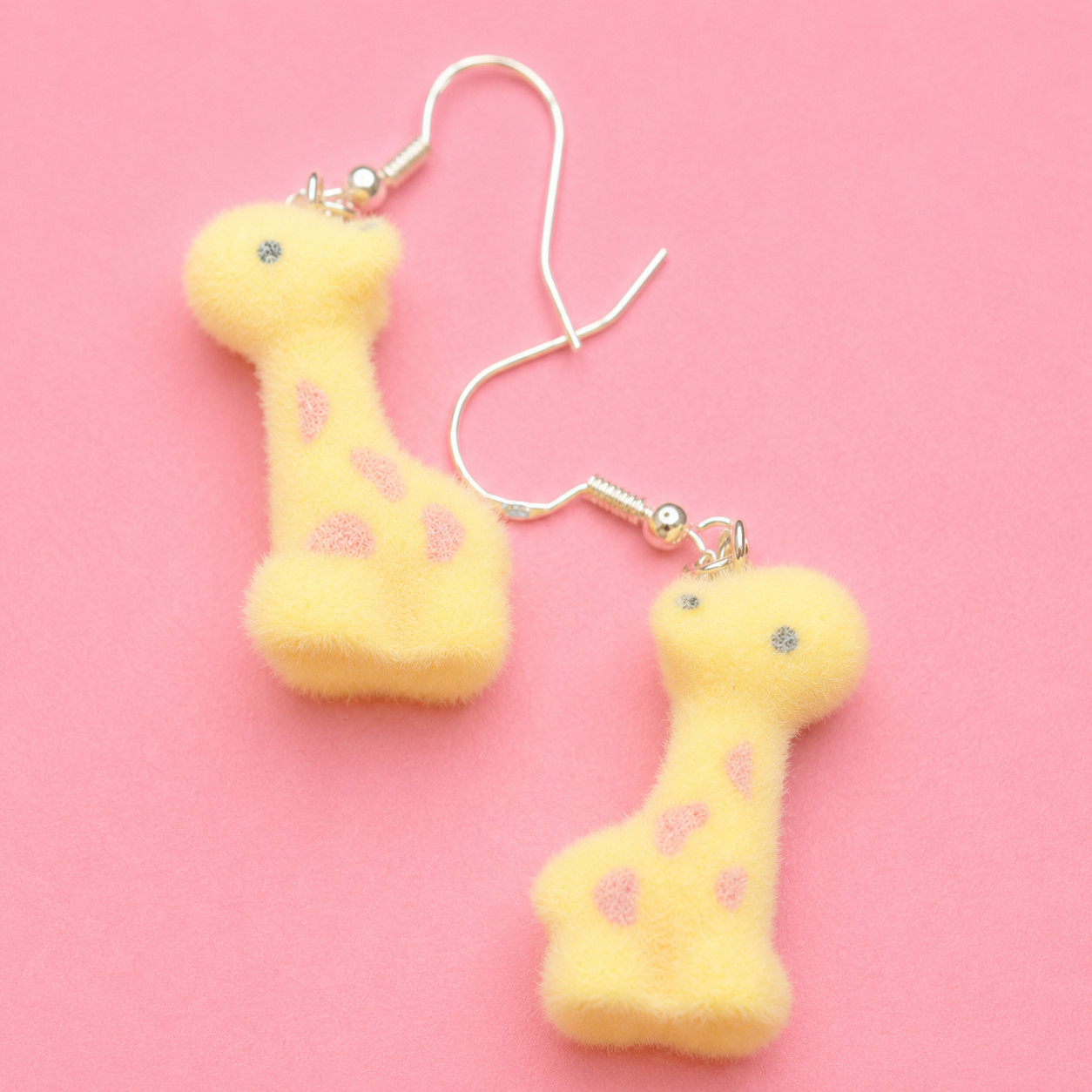Yellow dumbbell-shaped earrings on a pink background