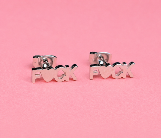 Silver 'F*ck' earrings on a pink background