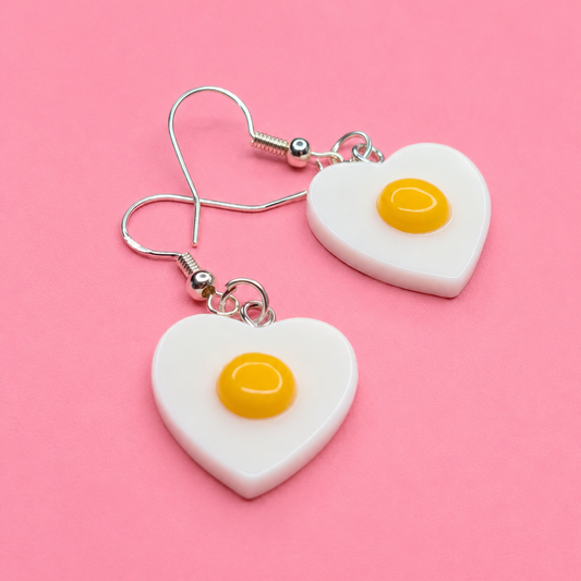 Heart-shaped earrings with egg design on a pink background