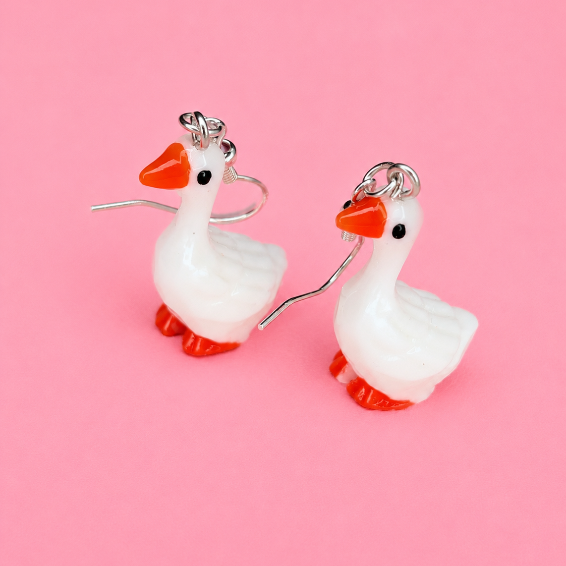 Goose-shaped earrings on a pink background
