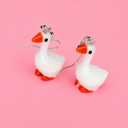 Goose-shaped earrings on a pink background
