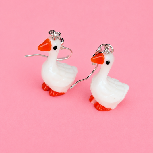 Goose-shaped earrings on a pink background